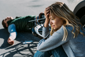 woman looks worried about bike accident as man lies on the ground