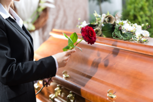 a person putting a rose on a coffin