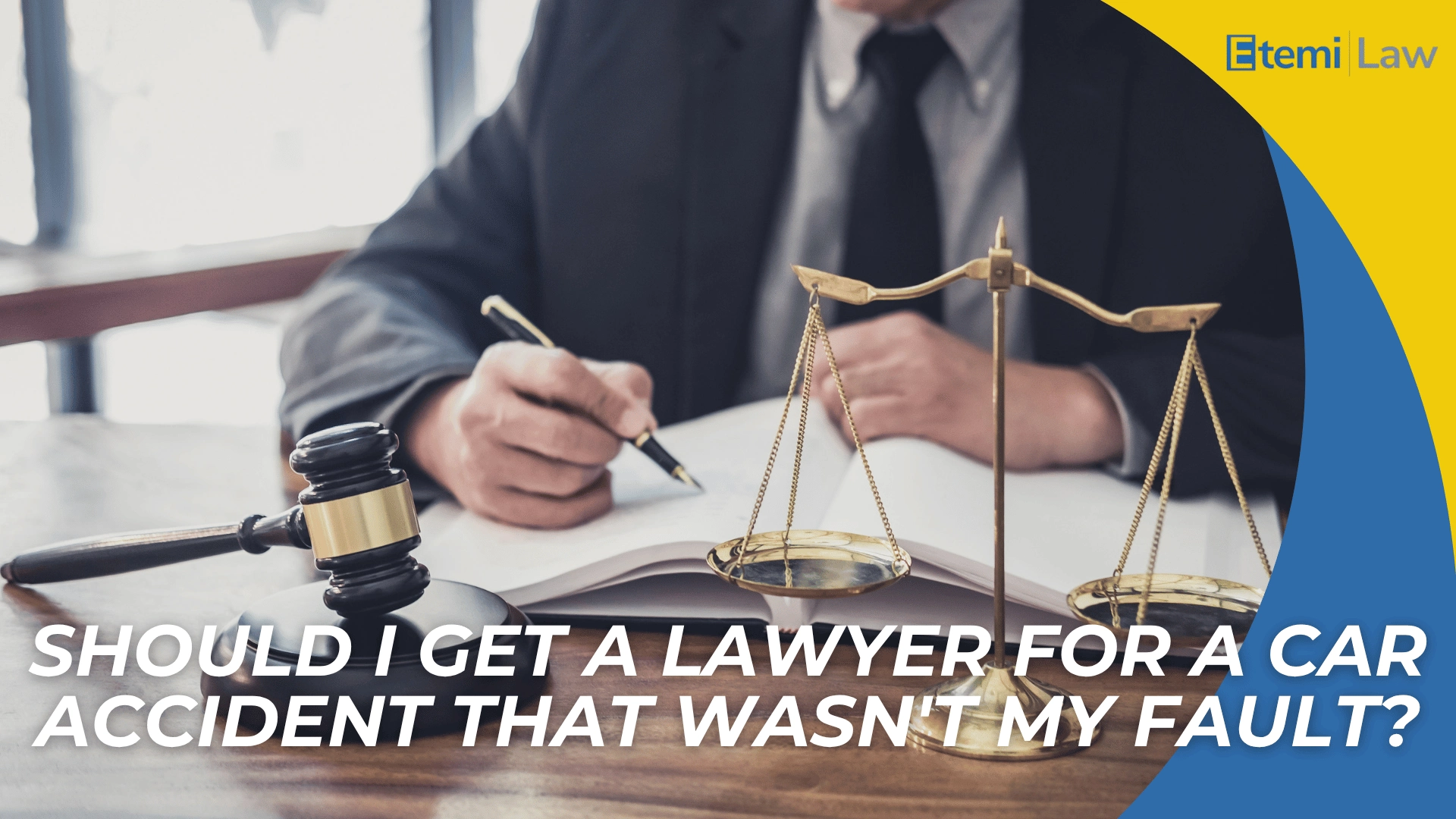 Gavel and scales on desk with person writing, introducing question about hiring a lawyer after a car accident